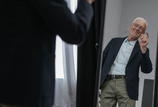 Senior man looks happily at his reflection in the mirror, capturing a joyful moment indoors.