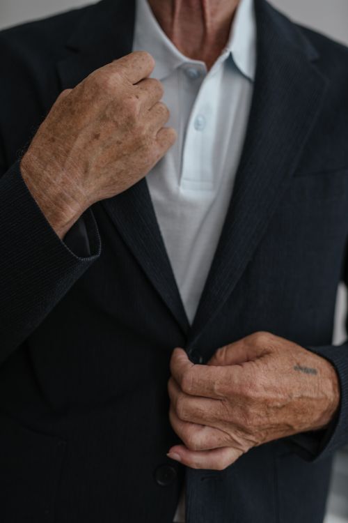 Free A senior man adjusting his suit jacket, emphasizing his hands and attire. Stock Photo