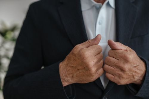 Free Senior adult man adjusting his formal suit jacket, highlighting hands and details of the fabric. Stock Photo