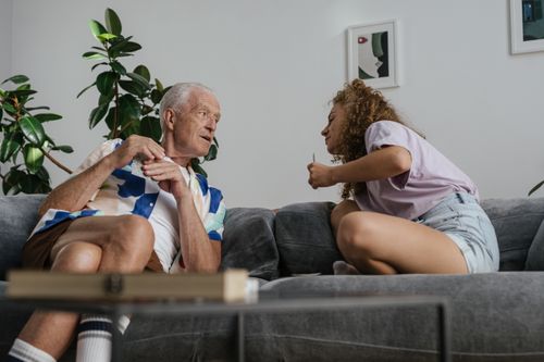 Free A grandfather and granddaughter enjoying leisure time indoors, sitting together on a sofa. Stock Photo