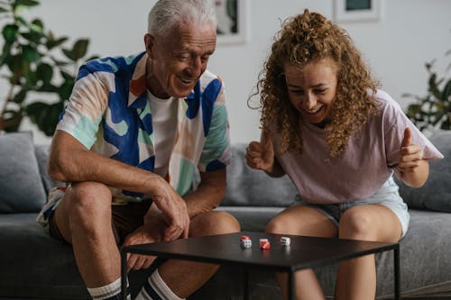 Elderly Man and a Woman Happy Looking at the Rolling Dices on the Table 