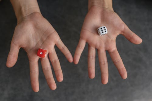 White and Red Dice on Person's Hand