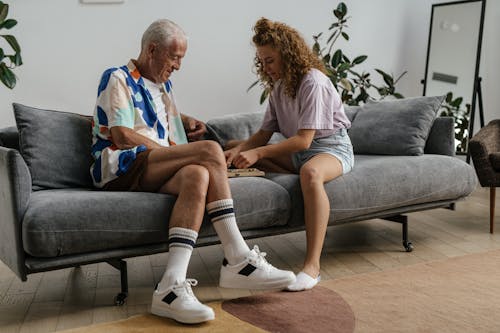 Free Elderly Man and Woman Sitting on Gray Couch While Playing Together  Stock Photo