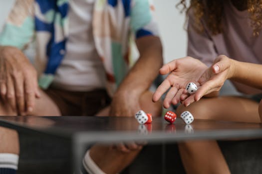 Two people playing a dice game, showcasing hands and rolling dice on a table.