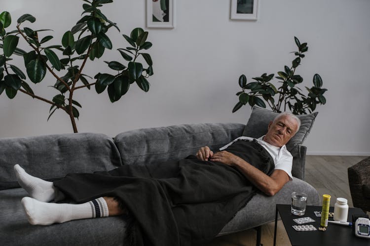 Sick Man Sleeping On The Gray Sofa