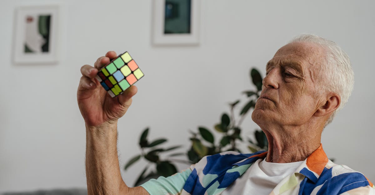 Senior adult contemplating a Rubik's Cube with focus and determination indoors.