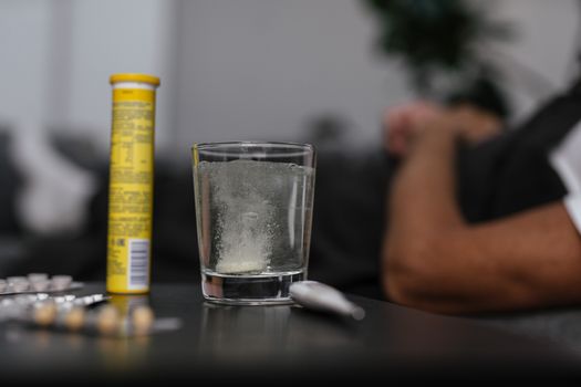 Effervescent tablet dissolving in glass, surrounded by medications, provides a healthcare-focused scene.