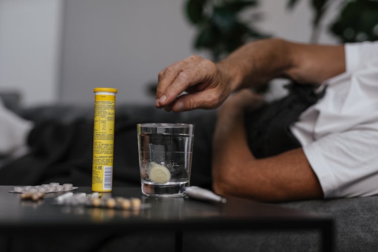 Person Putting Medicine On The Glass Of Water 