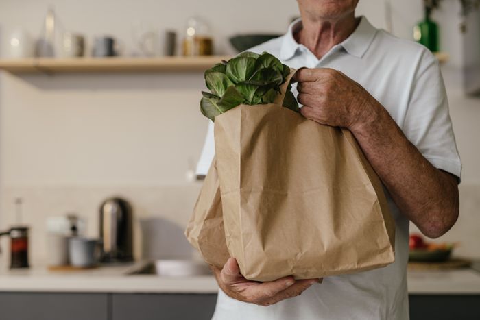 Man carrying heavy paper grocery bag with vegetables