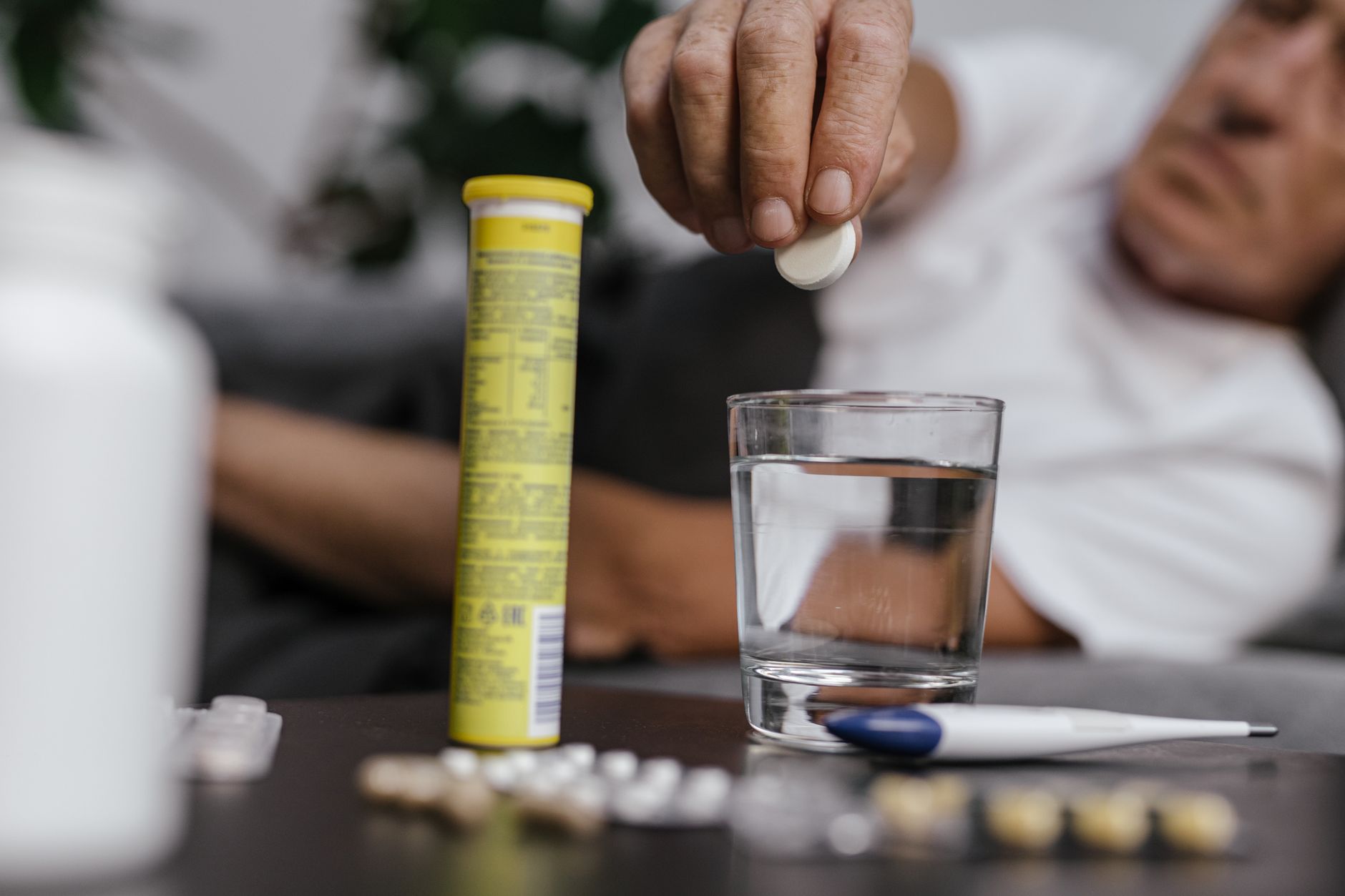 Various cold and flu medicine bottles and tablets on a wooden table