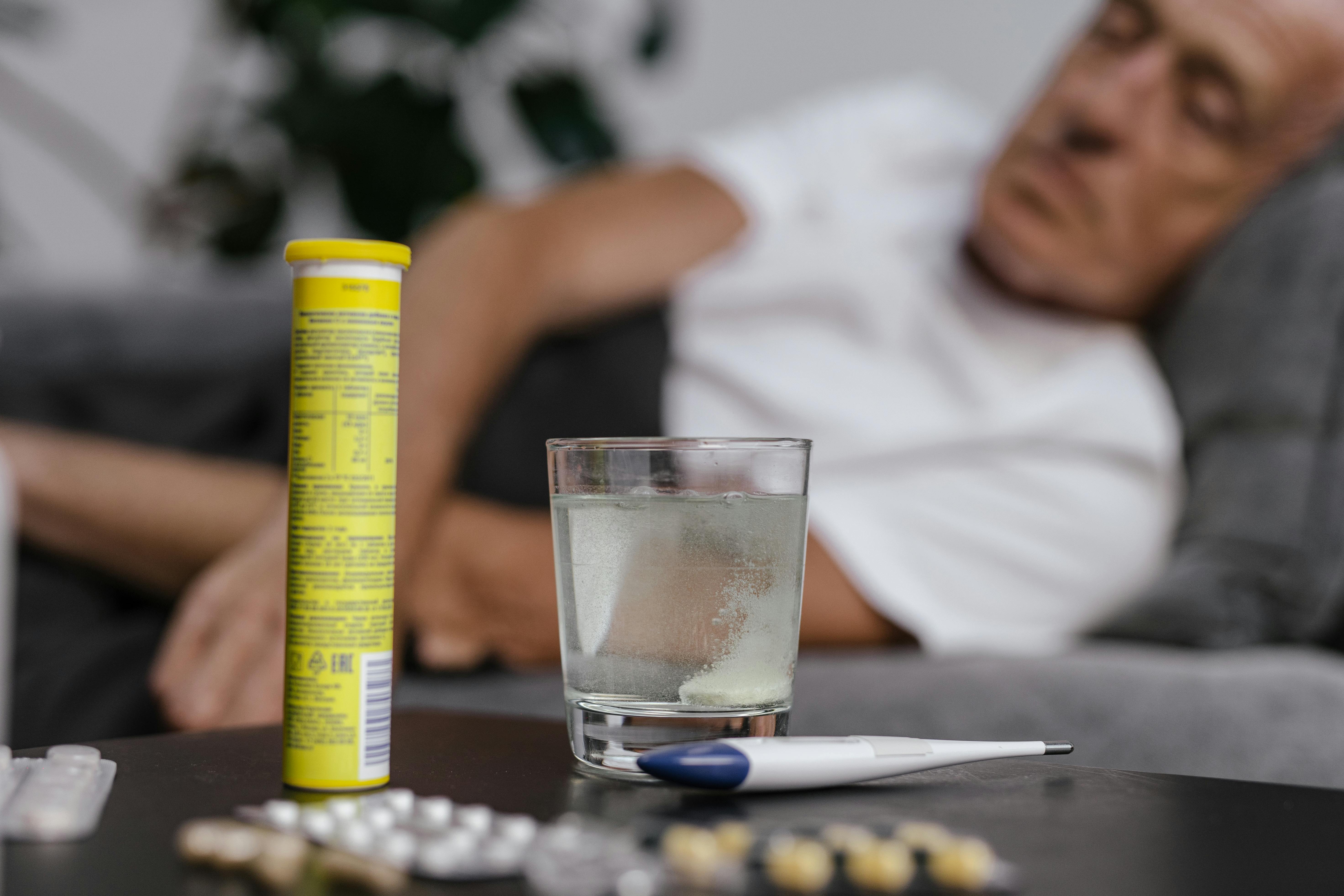 An elderly man resting on a couch with medicine, illustrating recovery or illness.