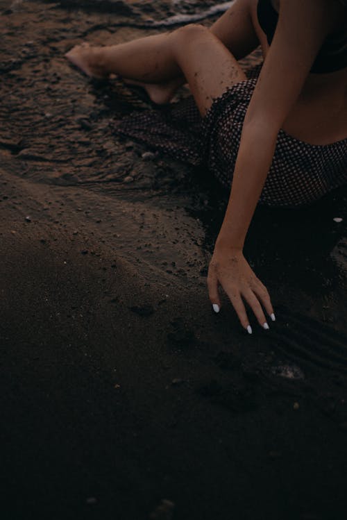 Woman Sitting on Dark Sand