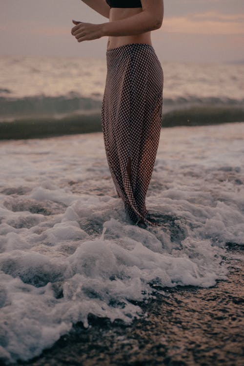 A Person in Brown and White Pants Standing on the Beach