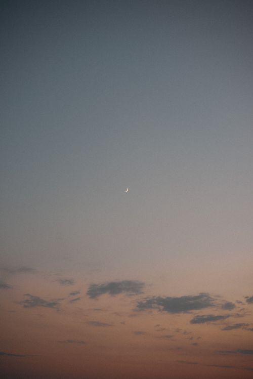 Free A peaceful twilight sky featuring a crescent moon and soft clouds, captured during sunset. Stock Photo