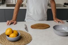 Adult man standing in a modern kitchen preparing to slice lemons with a knife.