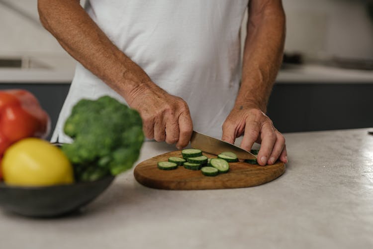 Person In White T-shirt Slicing Cucumber