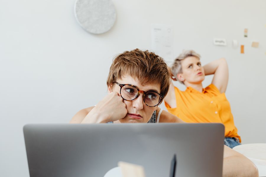Two women in a home office setting, focused on work while using a laptop.