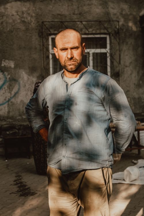 Free A bald man with facial hair posing outdoors, showcasing shadows and light contrasts. Stock Photo