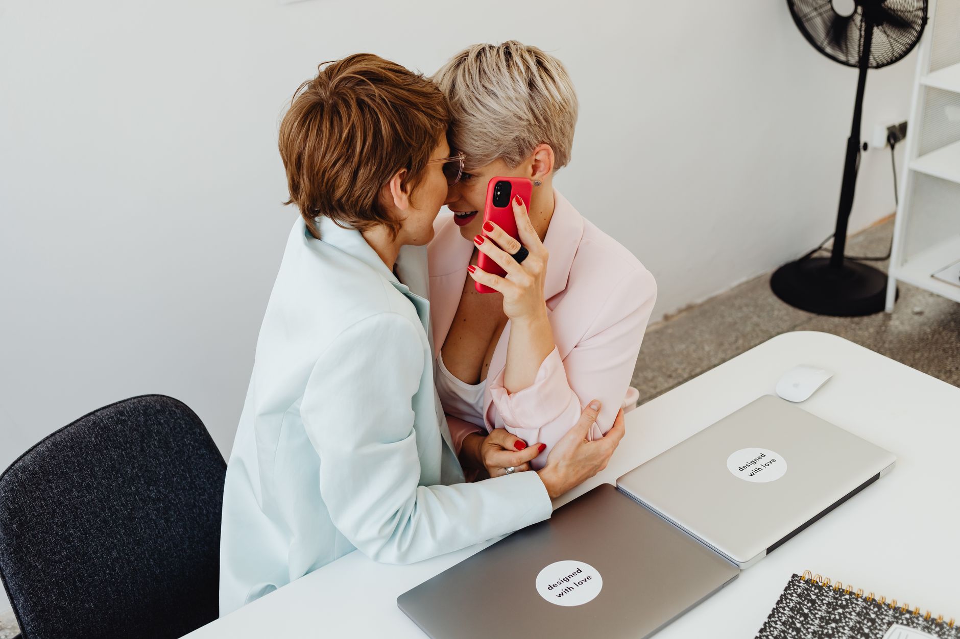 Two women enjoying a cozy moment at the office, embodying business diversity and collaboration.