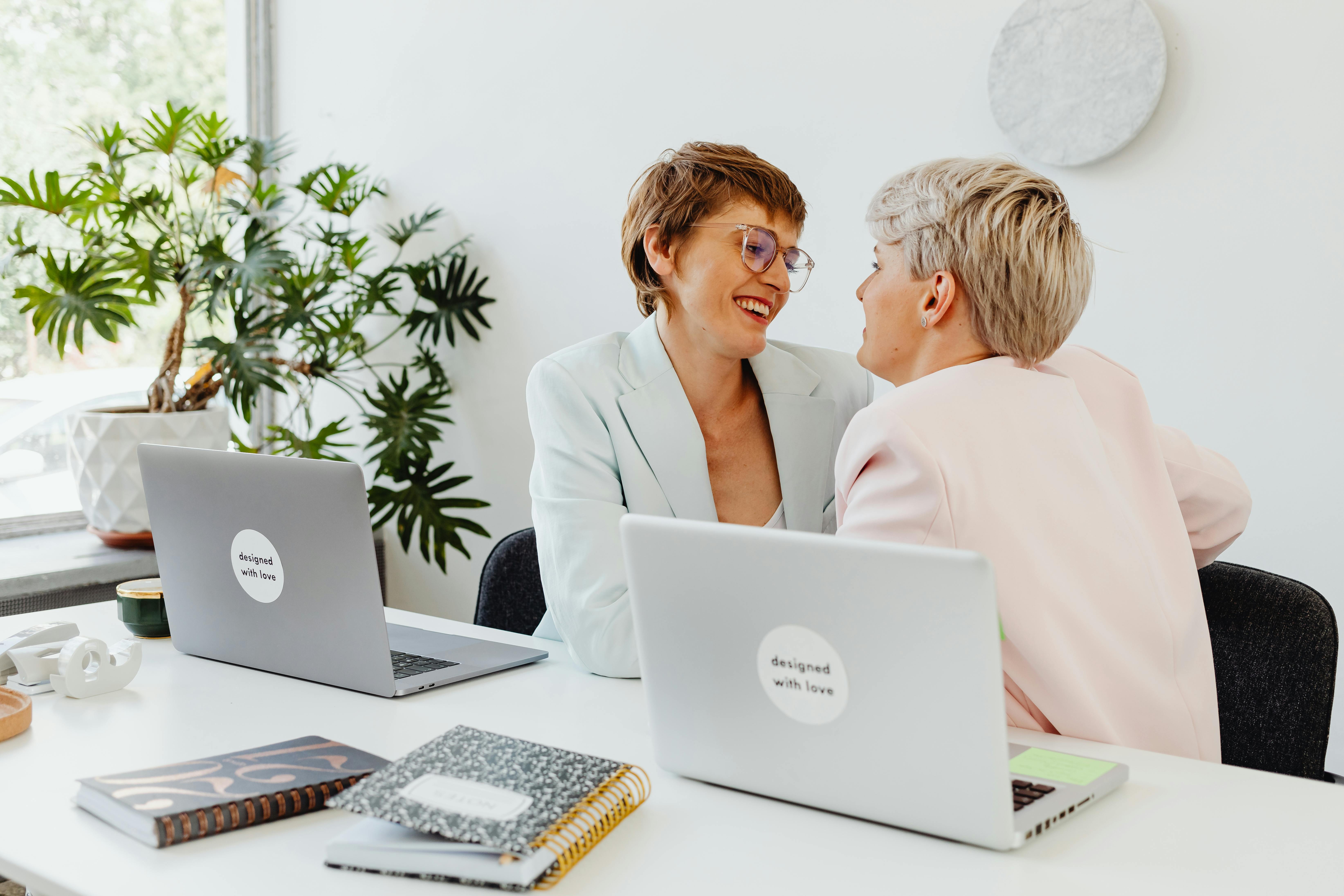 woman in white blazer sitting beside woman in pink blazer