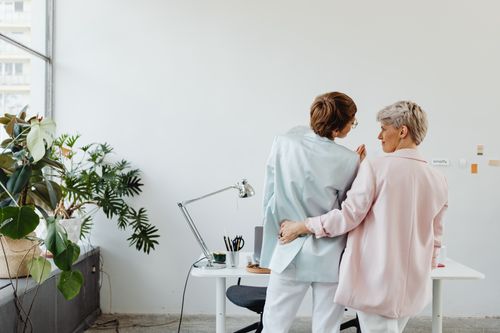 Free A loving lesbian couple embracing in an office, reflecting warmth and inclusivity. Stock Photo