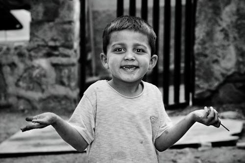 Monochrome Photo of a Kid Smiling while Looking at the Camera