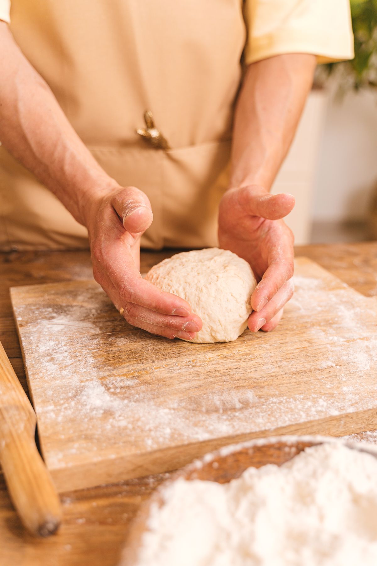 Mains qui travaillent une pâte sur un plan fariné