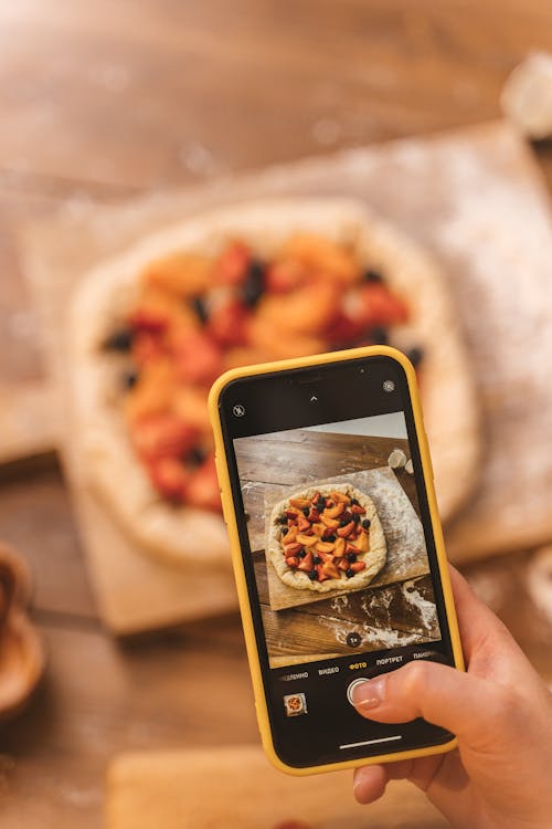 Hand Taking Picture of Fruit on Cake