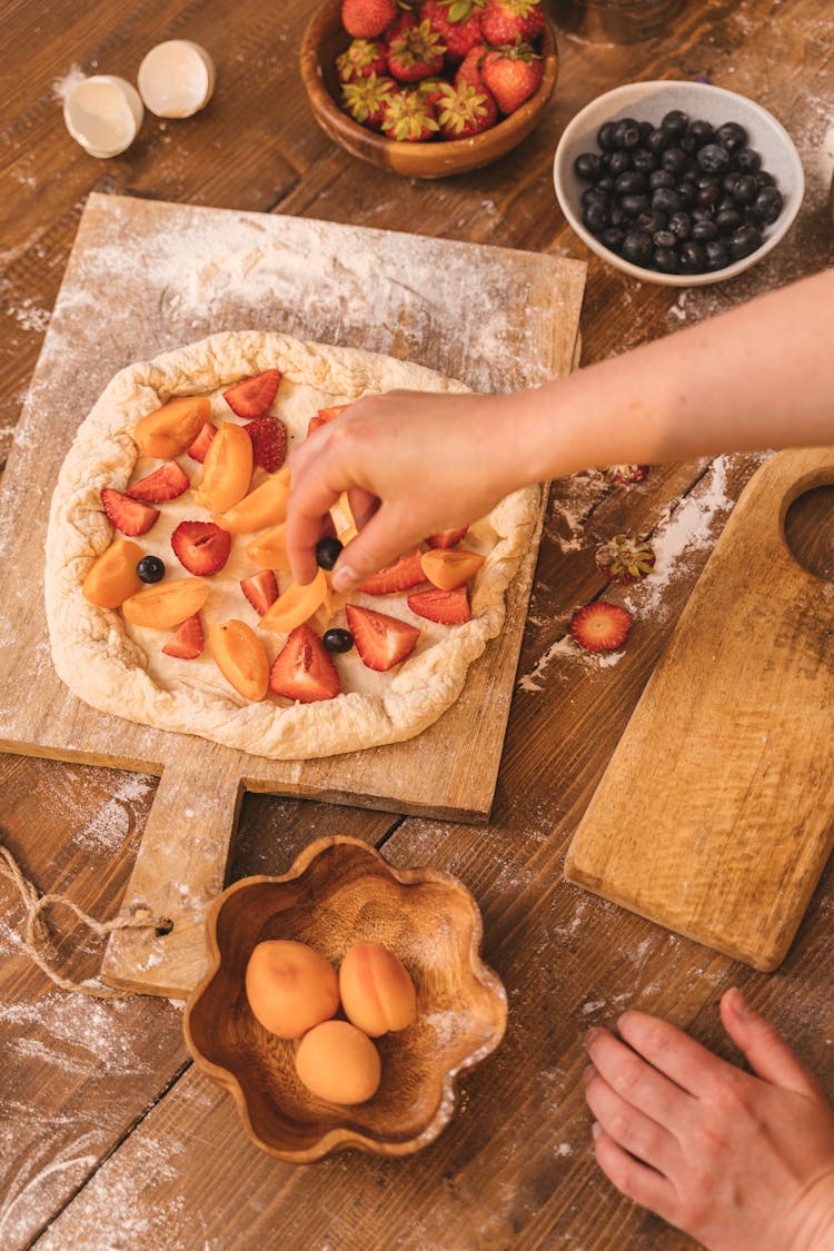 Person Adding Ingredients To A Fruit Galette