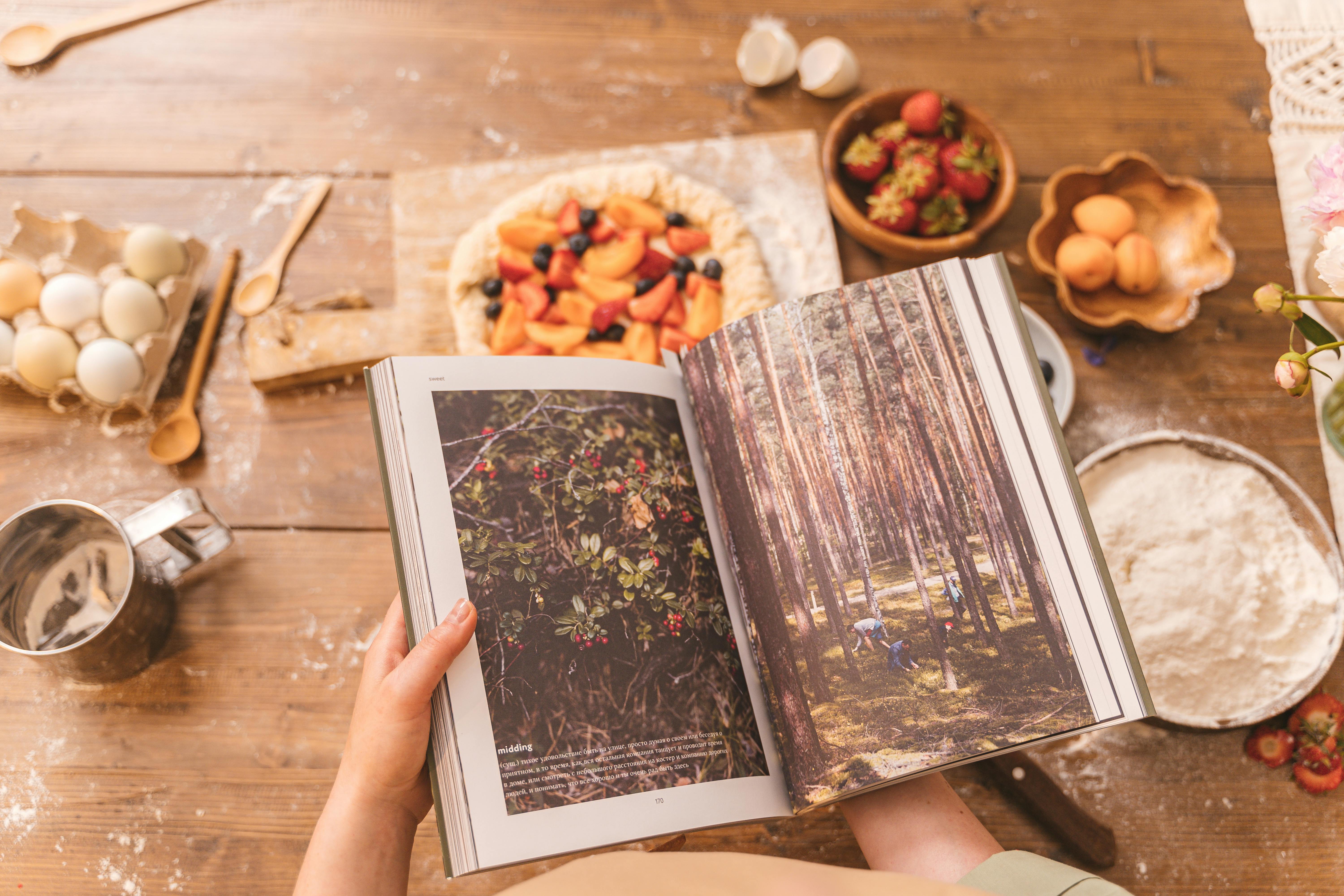 a person holding a book near brown wooden surface