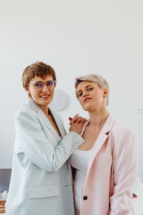 Free Two confident women in pastel business suits posing indoors with a bright and cheerful demeanor Stock Photo