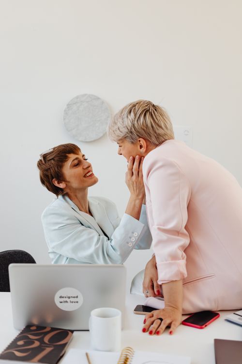 Free Lesbian couple showing affection and happiness in an office environment. Stock Photo