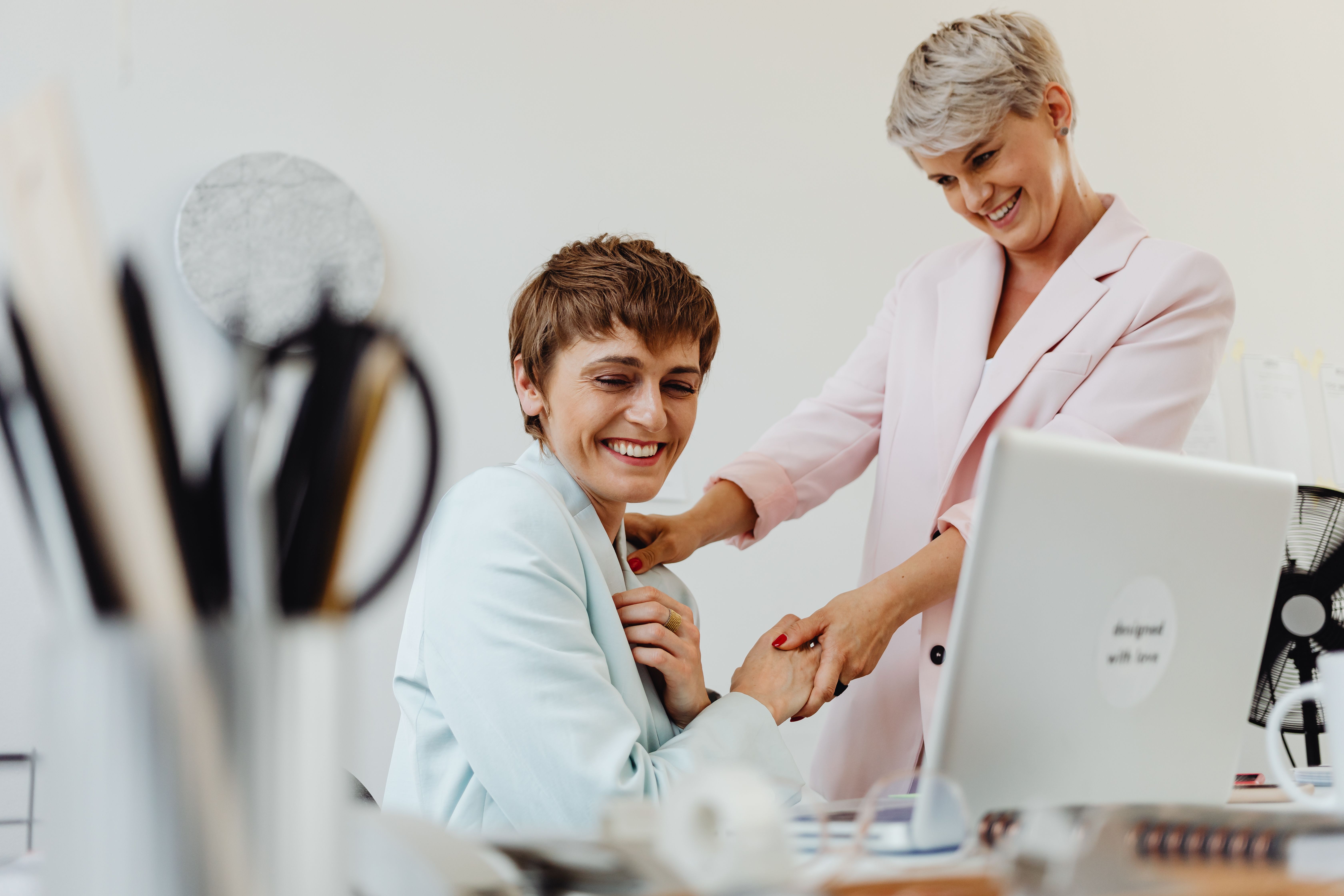 Two women in an office sharing a happy moment together at work