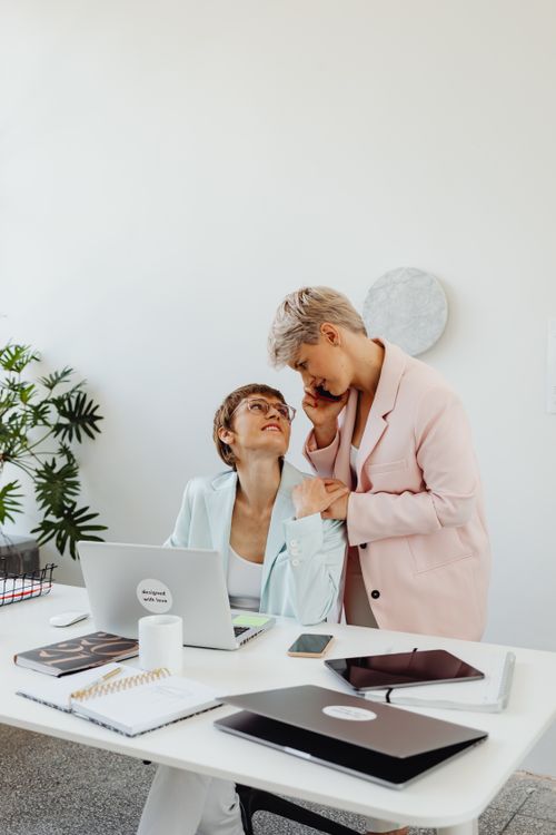 Free Two women share a close, intimate moment at a modern office workspace. Stock Photo