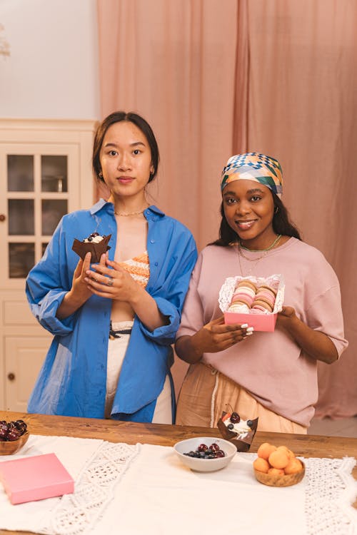 Woman in Blue Long Sleeve Shirt Holding Brown Cupcake