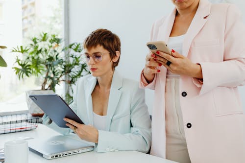 Women in Blazers Holding Electronic Devices