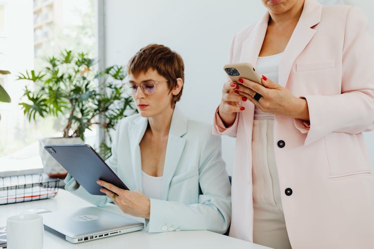 Women In Blazers Holding Electronic Devices