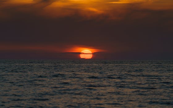 A breathtaking view of the ocean at sunset, featuring dramatic skies and golden hour lighting.