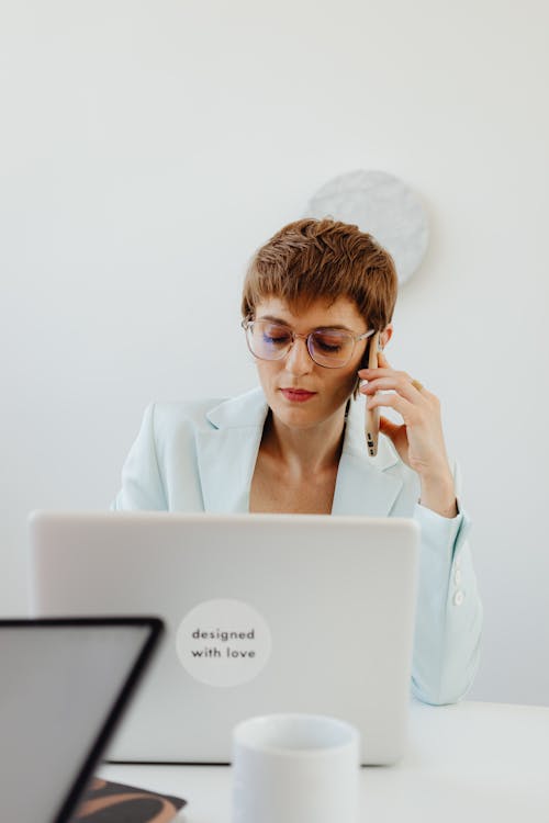 Woman in White Blazer Sitting Down while Talking on the Phone