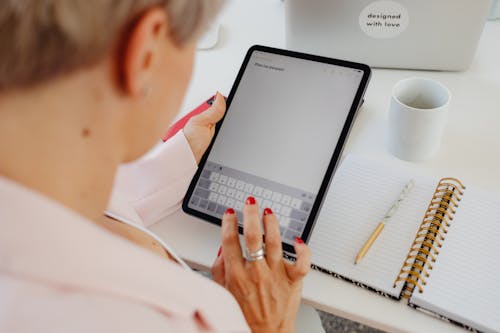 Woman in White Long Sleeve Shirt Using Black Digital Tablet 