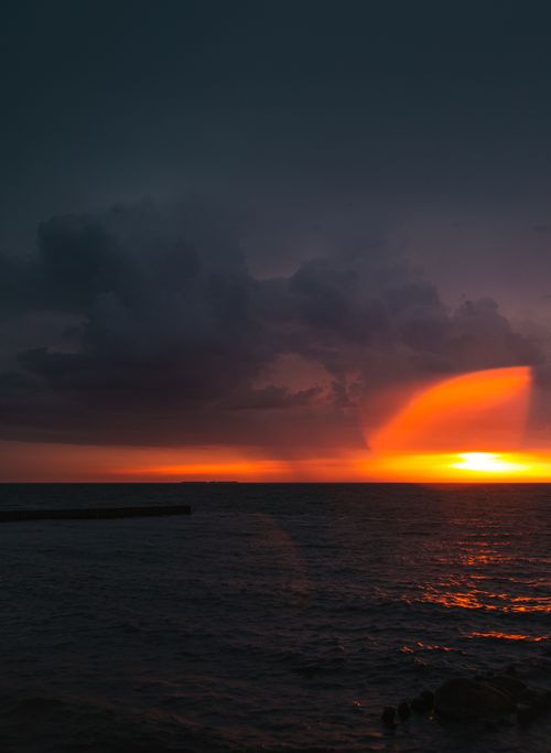 Free Breathtaking seascape capturing a dramatic sunset with stormy clouds and vivid colors over the ocean. Stock Photo