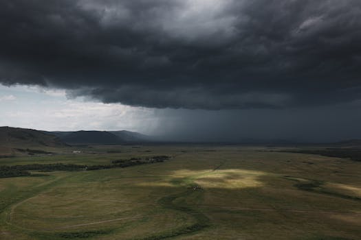 Dark storm clouds cast dramatic shadows over a lush green valley.