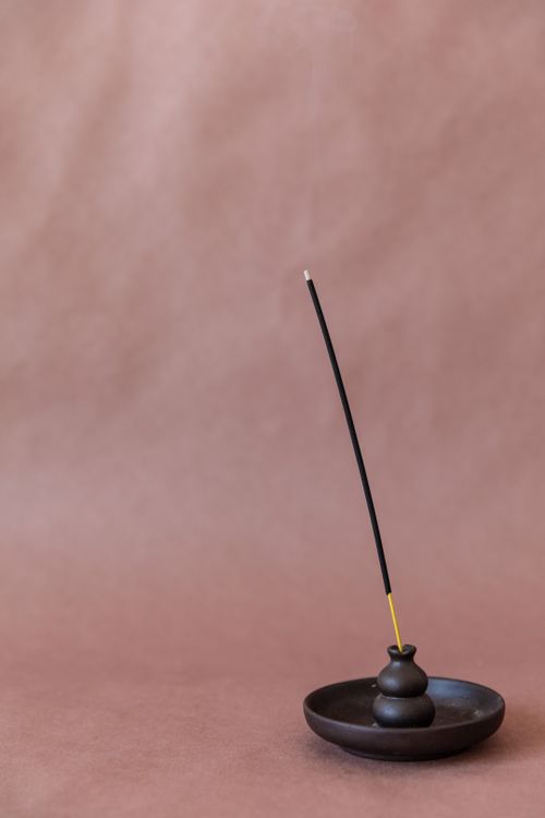 Free Elevate your senses with a burning incense stick on a soft brown backdrop. Stock Photo