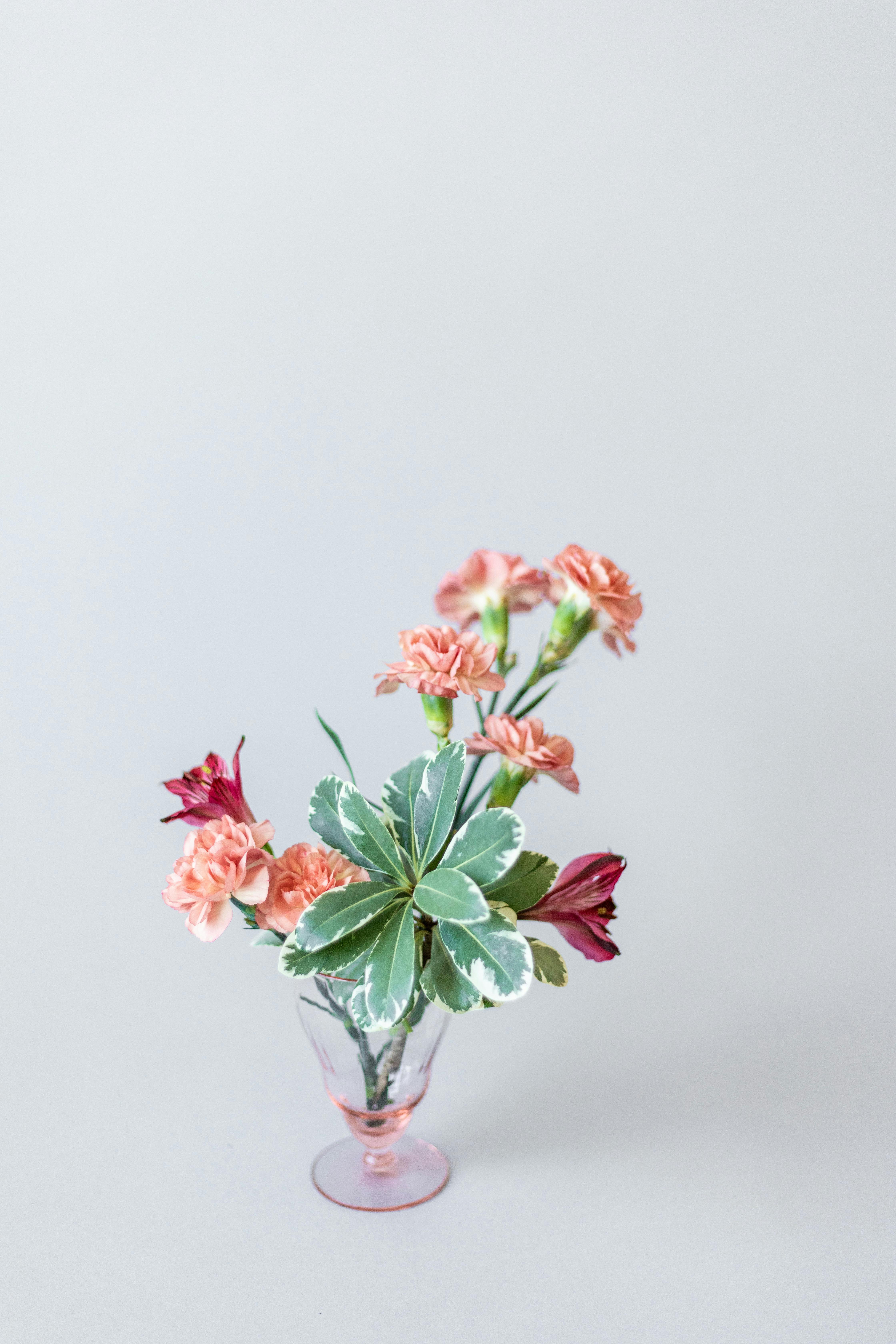 A delicate arrangement of pink flowers in a stylish vase on a soft gray background.