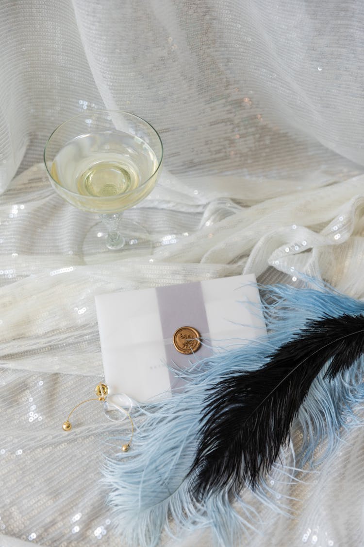 Feathers Beside White Sealed Card On Tulle Fabric