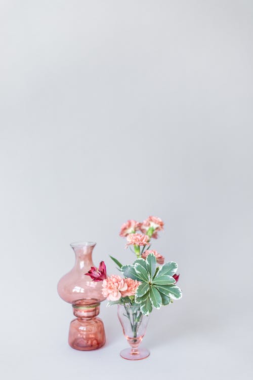 Pink and White Flowers in a Glass Vase Beside an Empty Glass Vase