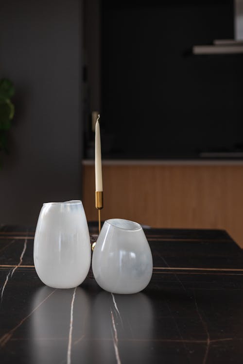 White Glass Vases and a Candle on a Black Surface