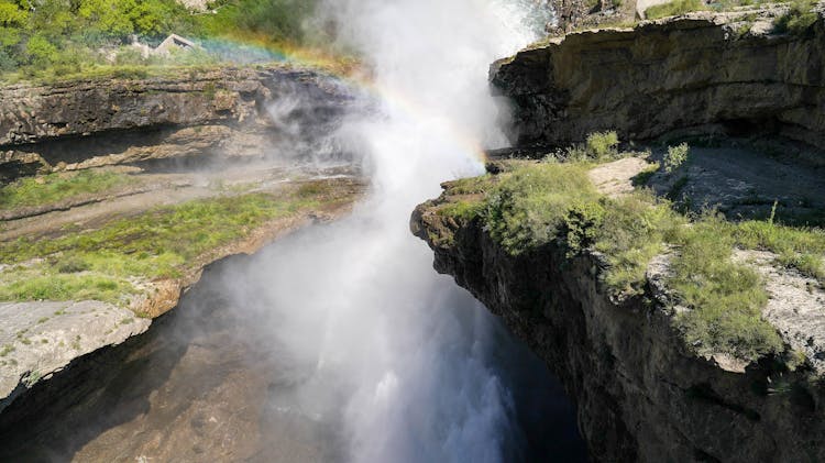 Rainbow Arching Against A Splashing Waterfall