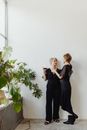 Woman in Black Long Sleeve Dress Standing Beside Green Plant