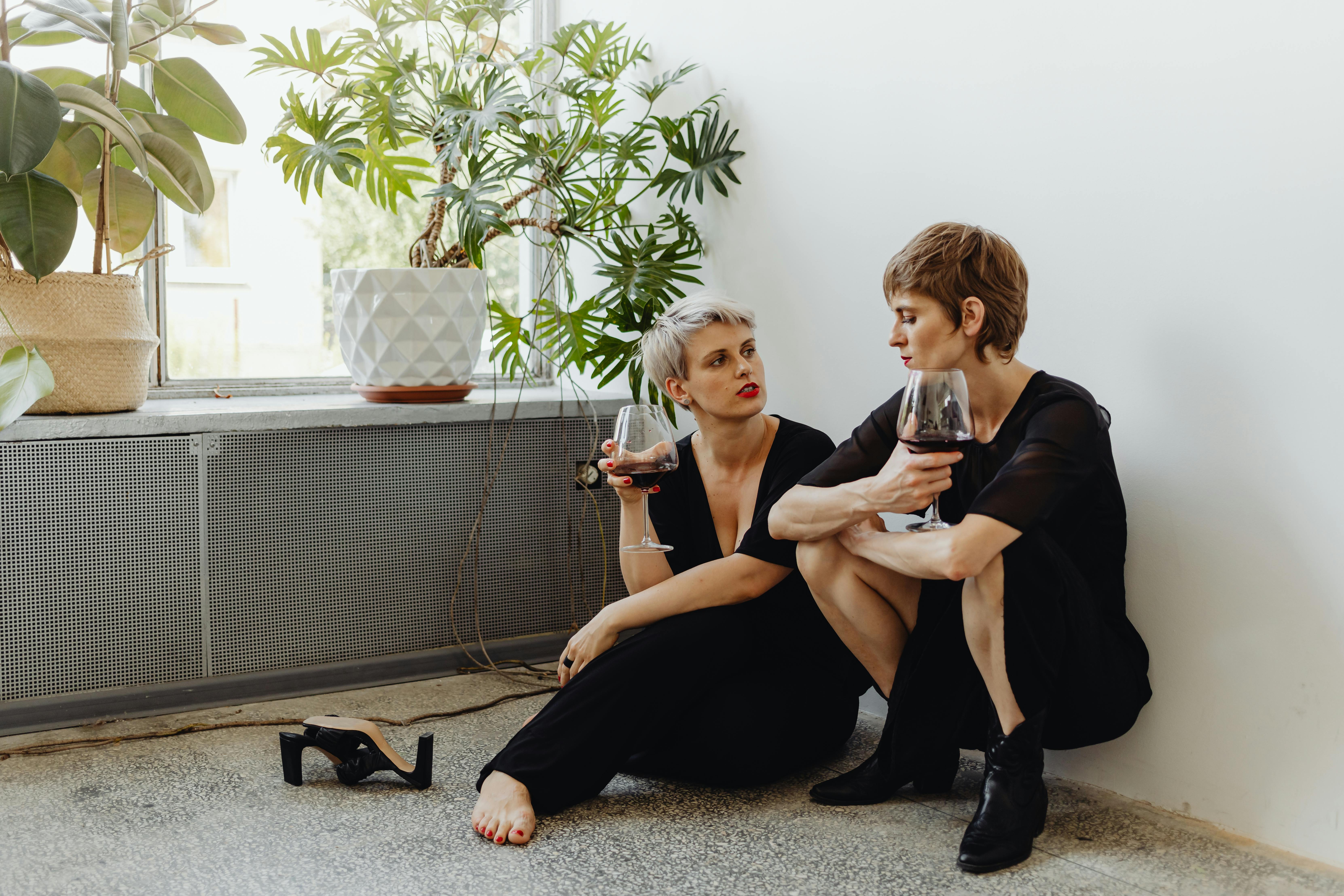 woman in black dress sitting on gray concrete floor